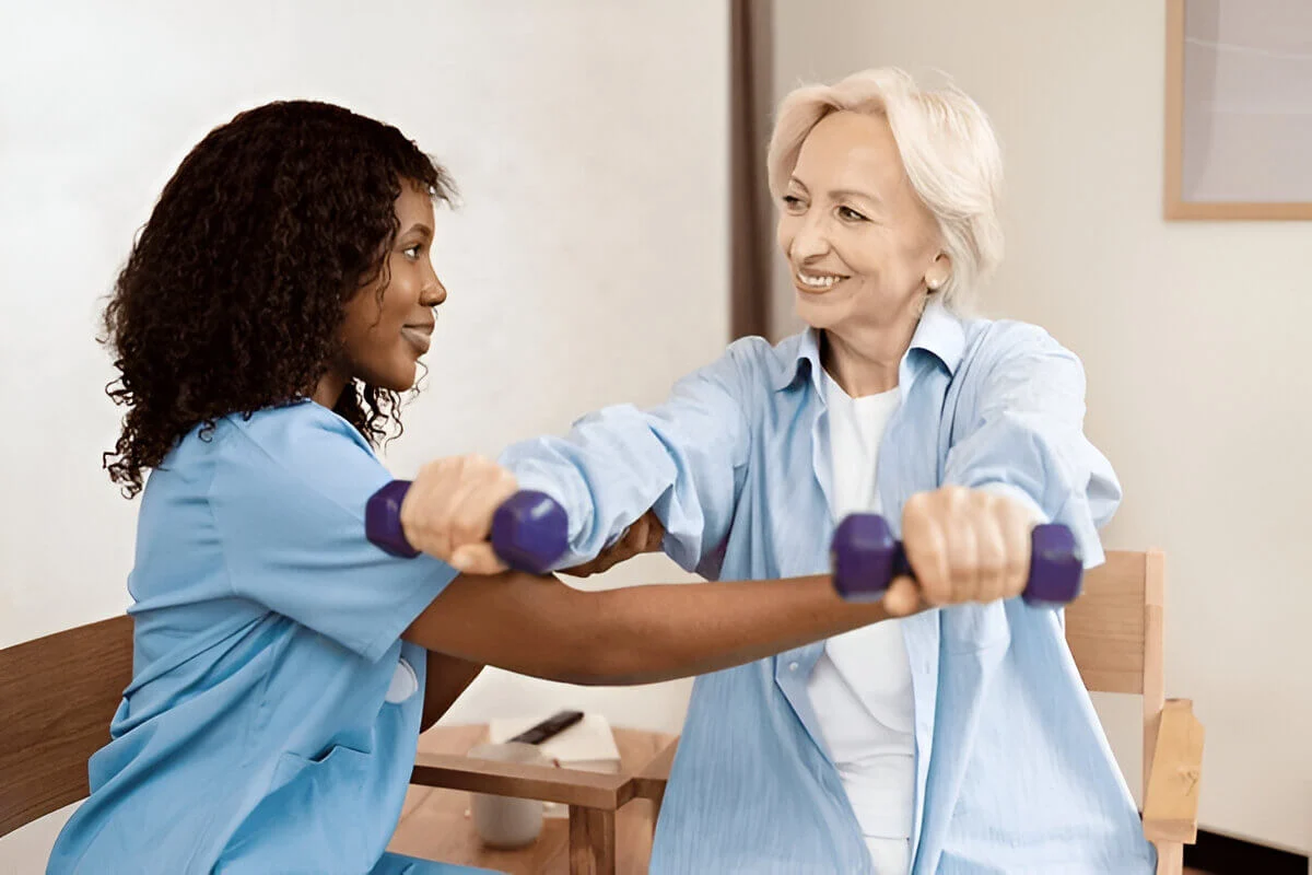Senior Woman Exercising With Nurse Using Dumbbells