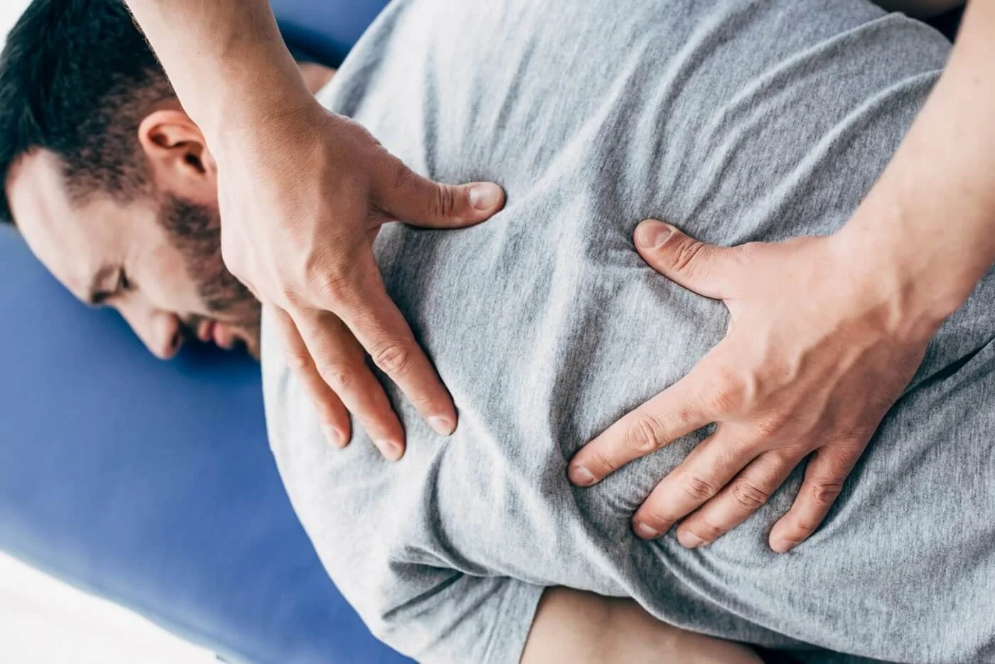 physiotherapist-massaging-back-of-man-lying-on-massage-table-in-hospital